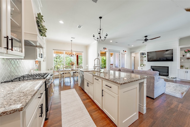 kitchen with hanging light fixtures, a kitchen island with sink, white cabinetry, appliances with stainless steel finishes, and sink