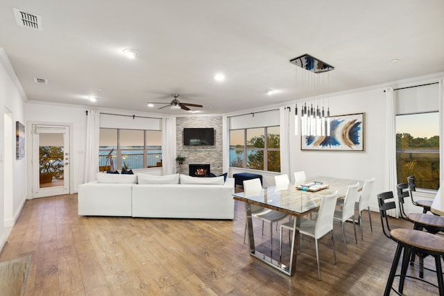 living room with ornamental molding, light hardwood / wood-style floors, a fireplace, and ceiling fan