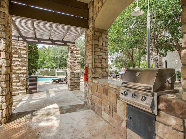 view of patio with grilling area, a fenced in pool, an outdoor kitchen, and a pergola