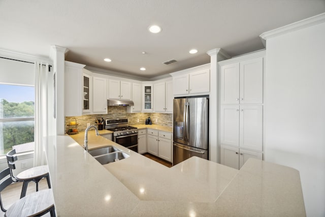 kitchen featuring appliances with stainless steel finishes, white cabinets, backsplash, kitchen peninsula, and sink