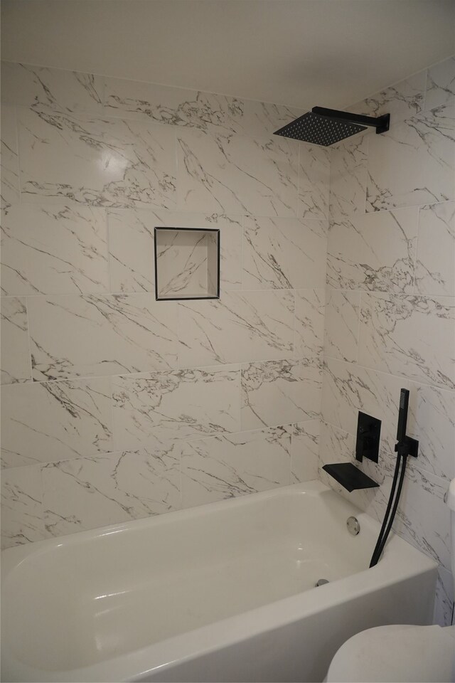 bathroom featuring tiled shower / bath and toilet