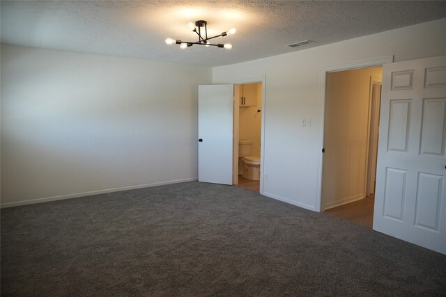 carpeted spare room featuring a textured ceiling and a notable chandelier