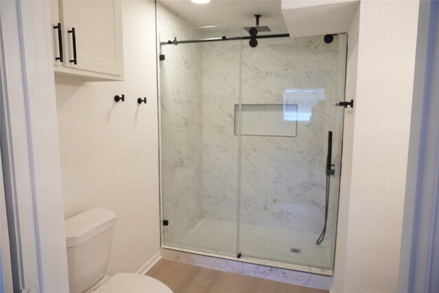 bathroom featuring a shower with door, toilet, and hardwood / wood-style flooring