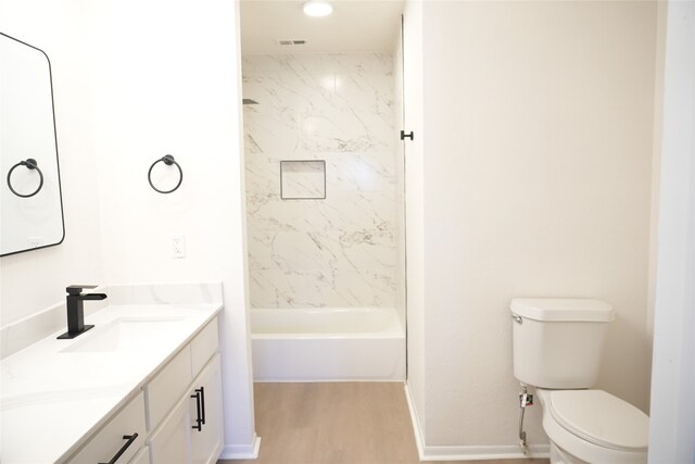 full bathroom with hardwood / wood-style floors, toilet, tiled shower / bath combo, and vanity