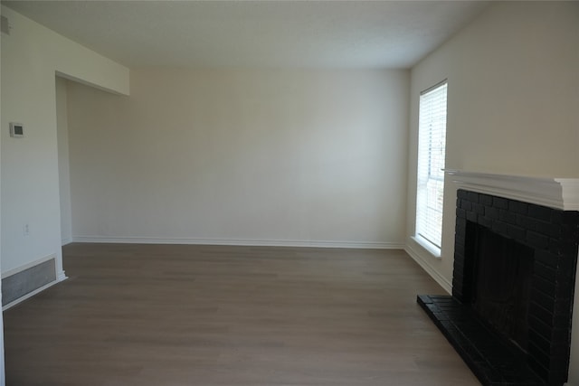 unfurnished living room featuring hardwood / wood-style flooring and a brick fireplace