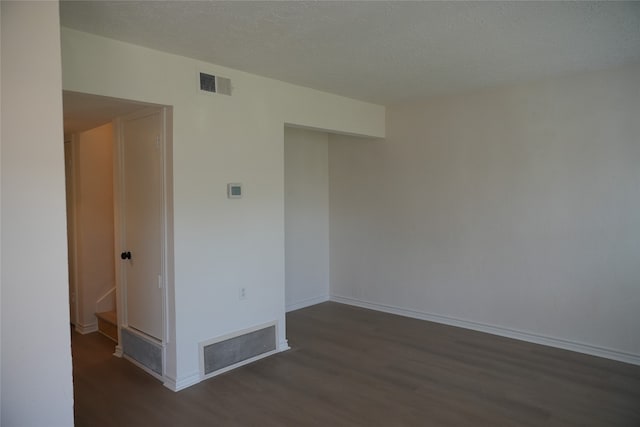 empty room featuring a textured ceiling and dark hardwood / wood-style flooring