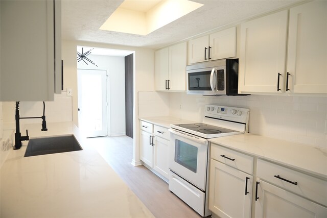 kitchen featuring white cabinetry, light hardwood / wood-style flooring, decorative backsplash, and white electric range