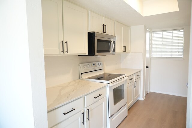 kitchen with white cabinets, backsplash, light stone counters, light hardwood / wood-style floors, and white electric stove