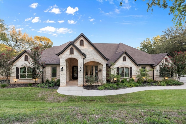 french country home with a front lawn and roof with shingles