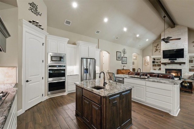 kitchen featuring appliances with stainless steel finishes, a center island with sink, a sink, and visible vents