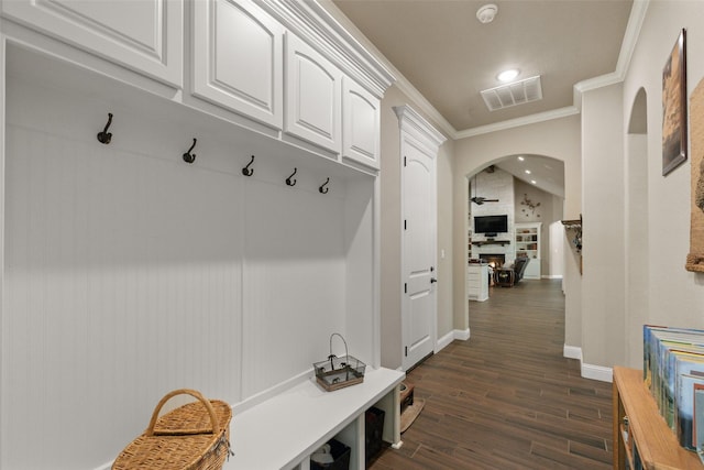 mudroom with dark wood-style floors, arched walkways, visible vents, ornamental molding, and baseboards