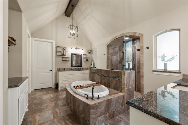 bathroom with two vanities, an inviting chandelier, a walk in shower, beamed ceiling, and a bath