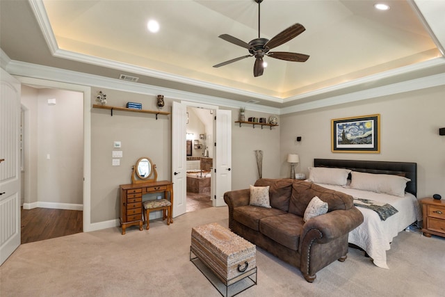 bedroom featuring ornamental molding, ceiling fan, a tray ceiling, light carpet, and ensuite bath