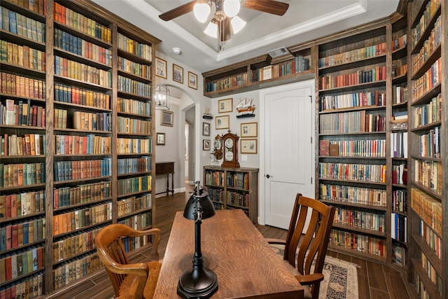 home office featuring dark hardwood / wood-style flooring, a tray ceiling, crown molding, and ceiling fan