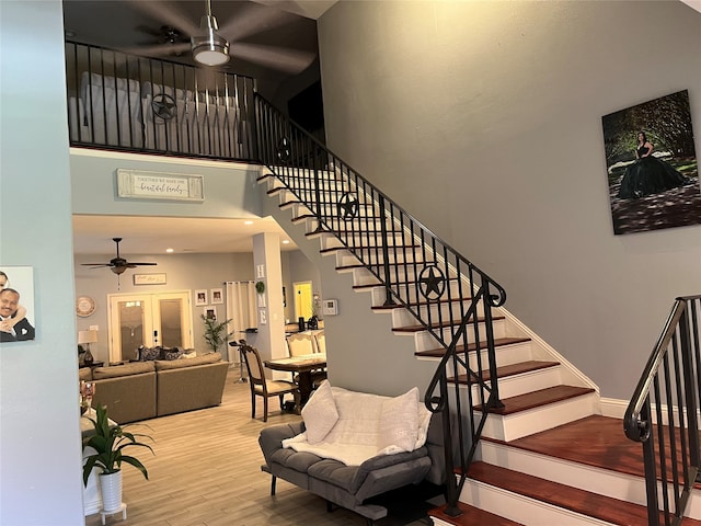 stairway featuring hardwood / wood-style flooring, ceiling fan, and a high ceiling