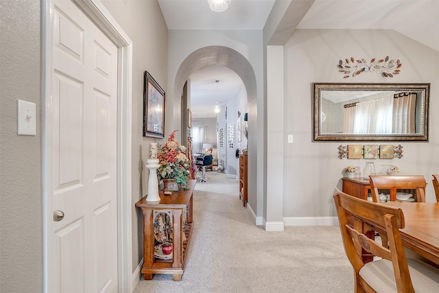 corridor with vaulted ceiling and light carpet