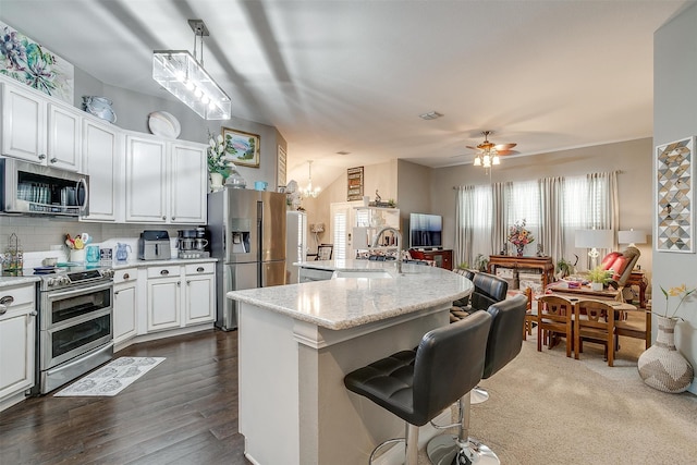 kitchen featuring ceiling fan with notable chandelier, pendant lighting, appliances with stainless steel finishes, dark wood-type flooring, and white cabinetry