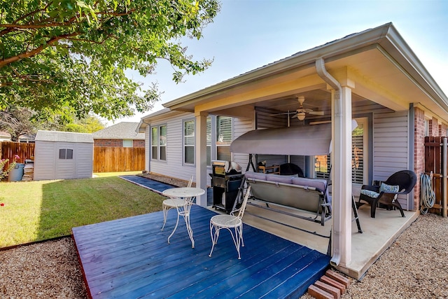 deck with ceiling fan, a storage shed, and a lawn