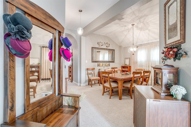 carpeted dining space featuring lofted ceiling and a chandelier