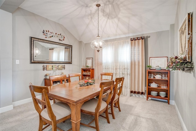 dining area with a notable chandelier, light carpet, and vaulted ceiling