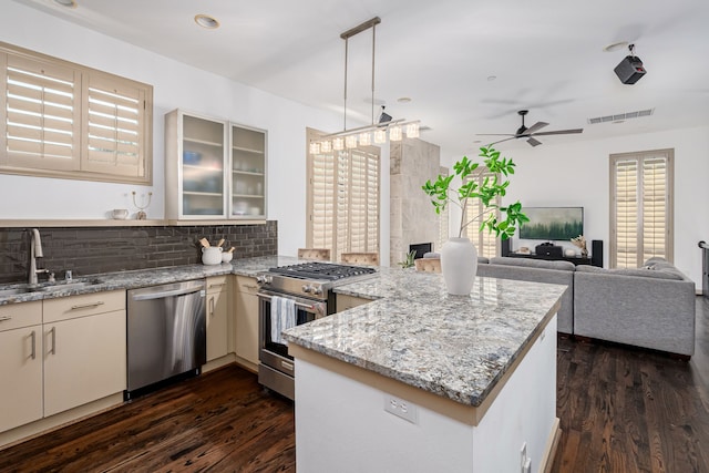 kitchen featuring dark hardwood / wood-style floors, sink, kitchen peninsula, stainless steel appliances, and ceiling fan