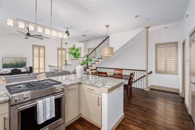 kitchen featuring ceiling fan, high end stove, dark hardwood / wood-style floors, and light stone counters