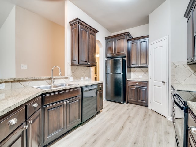 kitchen with black appliances, backsplash, sink, and light hardwood / wood-style floors