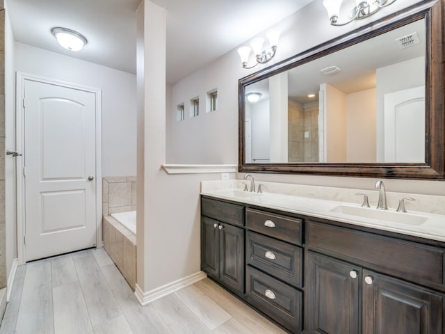 bathroom featuring tiled tub, vanity, and wood-type flooring