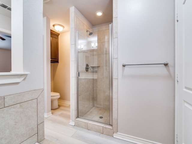 bathroom with toilet, wood-type flooring, and a shower with shower door