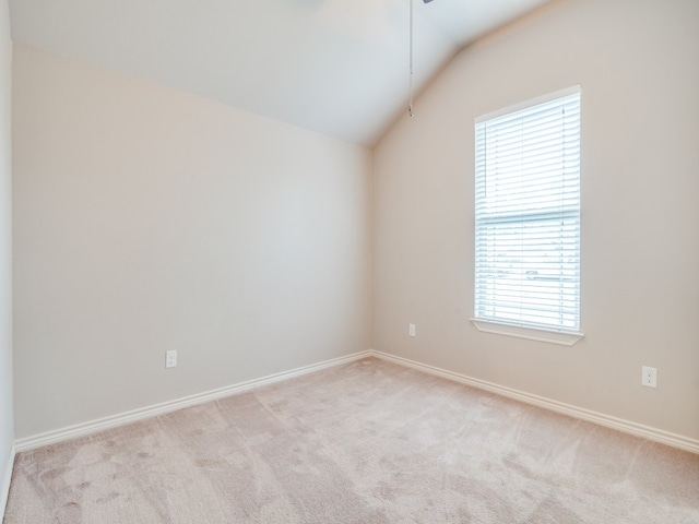 carpeted empty room featuring vaulted ceiling