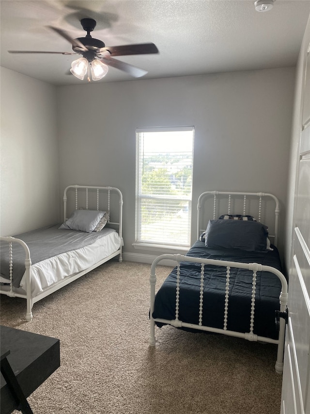 carpeted bedroom featuring ceiling fan and a textured ceiling