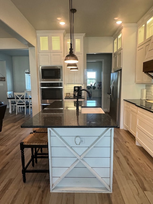 kitchen with decorative light fixtures, stainless steel appliances, dark hardwood / wood-style flooring, and white cabinetry