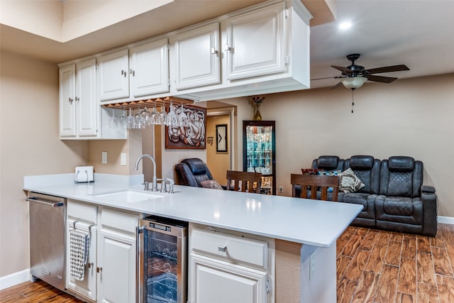 kitchen featuring wine cooler, kitchen peninsula, white cabinetry, and sink