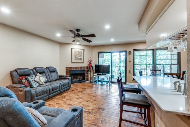 living room featuring a brick fireplace, hardwood / wood-style floors, and ceiling fan