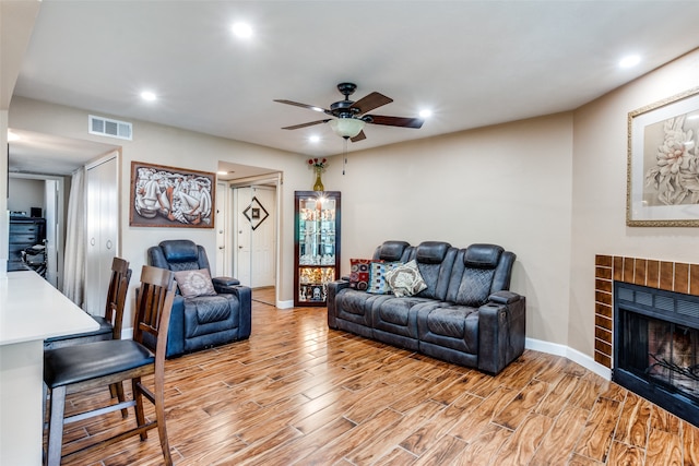 living room with light wood-type flooring, a fireplace, and ceiling fan