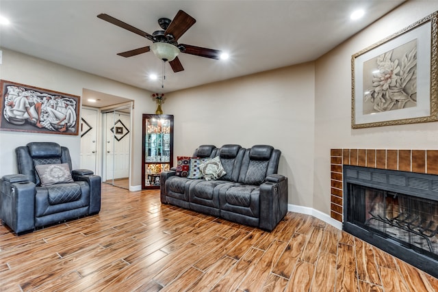 living room with ceiling fan, light hardwood / wood-style flooring, and a tile fireplace