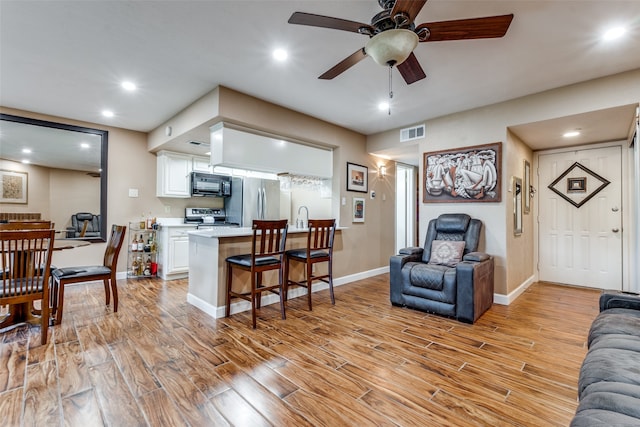 living room with ceiling fan and light hardwood / wood-style flooring