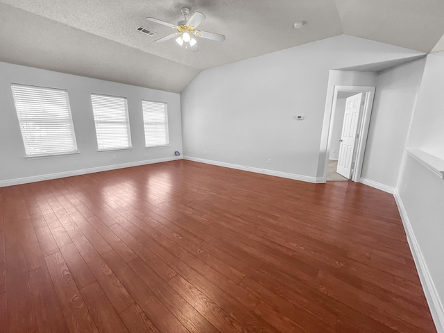 unfurnished living room with vaulted ceiling, a textured ceiling, dark hardwood / wood-style flooring, and ceiling fan