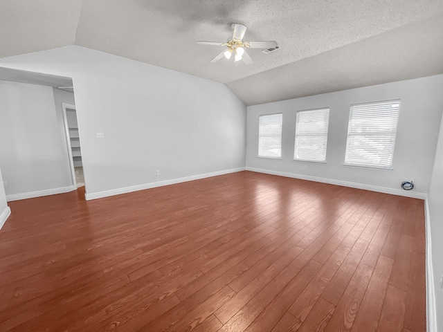 unfurnished room featuring lofted ceiling, ceiling fan, dark hardwood / wood-style flooring, and a textured ceiling