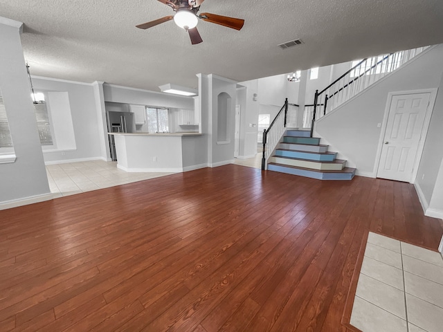 unfurnished living room with ceiling fan with notable chandelier, a textured ceiling, and light hardwood / wood-style floors