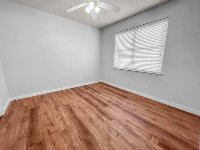 spare room with a textured ceiling, ceiling fan, and light wood-type flooring