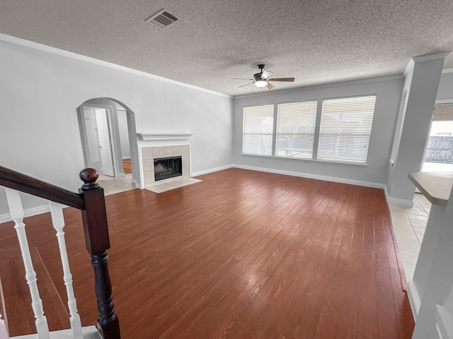 unfurnished living room featuring a healthy amount of sunlight, ceiling fan, a tile fireplace, and hardwood / wood-style flooring