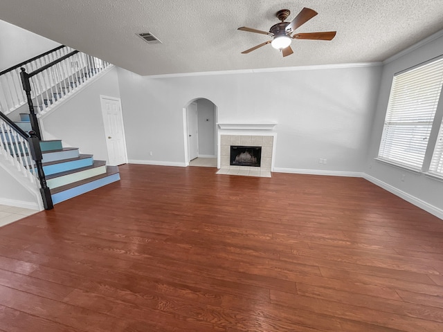 unfurnished living room featuring a fireplace, a textured ceiling, dark wood-type flooring, ceiling fan, and ornamental molding