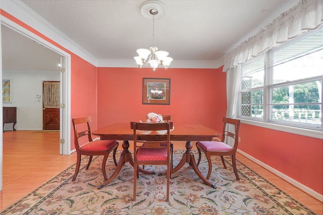 dining room with light wood-type flooring, a notable chandelier, ornamental molding, and a textured ceiling