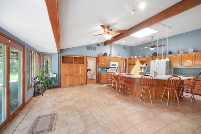 kitchen with pendant lighting, white appliances, a kitchen island, a kitchen bar, and lofted ceiling with skylight