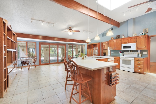 kitchen with ceiling fan, sink, white appliances, a kitchen island with sink, and a textured ceiling