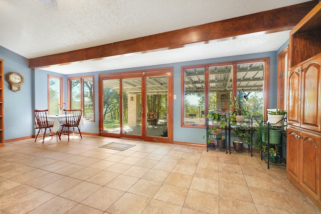 interior space featuring plenty of natural light, a textured ceiling, light tile patterned floors, and beam ceiling