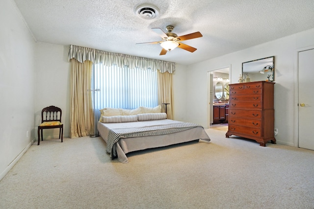 bedroom with light carpet, ceiling fan, a textured ceiling, and ensuite bath