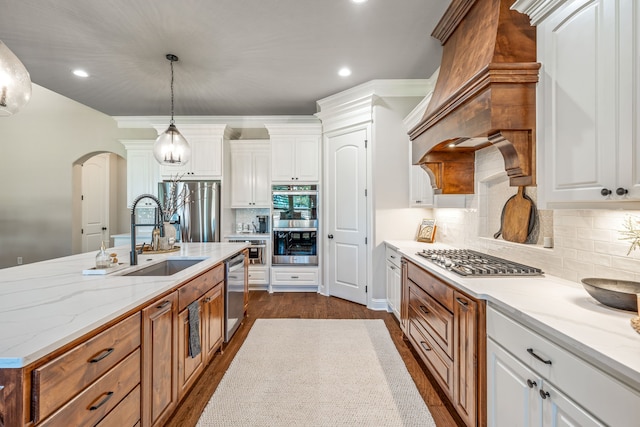 kitchen with appliances with stainless steel finishes, white cabinetry, decorative light fixtures, and sink