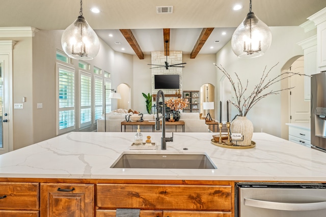 kitchen featuring pendant lighting, a center island with sink, beamed ceiling, and sink